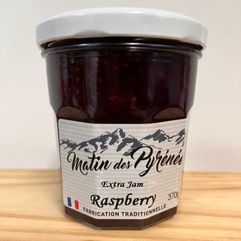 Jar of raspberry jam with a label on a wooden surface
